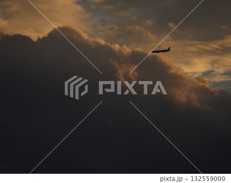 美しい夕焼けの空を飛ぶ飛行機 132559000