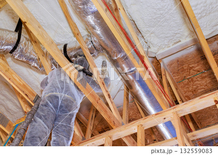 Construction worker is busy installing ductwork inside new home under construction, working on ceiling supports. Construction worker is busy installing ductwork inside new home under construction, working on ceiling supports. 132559083