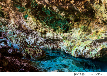 View of beautiful natural pool of crystal clear water formed in a rocky cave with stalagmites and stalagmites. Kuza cave in Zanzibar, Tanzania 132559520