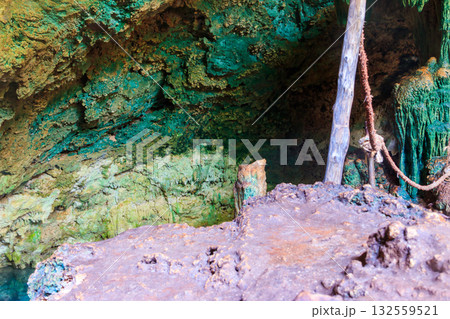 View of beautiful natural pool of crystal clear water formed in a rocky cave with stalagmites and stalagmites. Kuza cave in Zanzibar, Tanzania 132559521