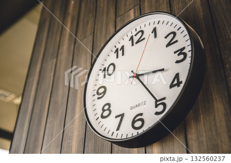 Time Clock hanging at modern wooden wall background, business times, office working hours concept. 132560237