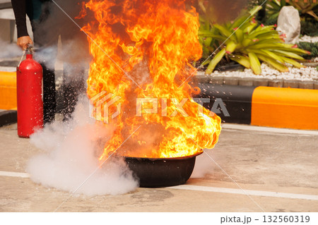 Firefighters use Fire extinguisher spraying chemical liquid fog gas to flame fire extinguishing 132560319
