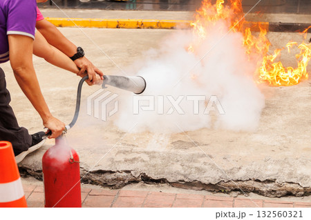 Firefighters use Fire extinguisher spraying chemical liquid fog gas to flame fire extinguishing 132560321