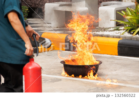 Firefighters use Fire extinguisher spraying chemical liquid fog gas to flame fire extinguishing 132560322
