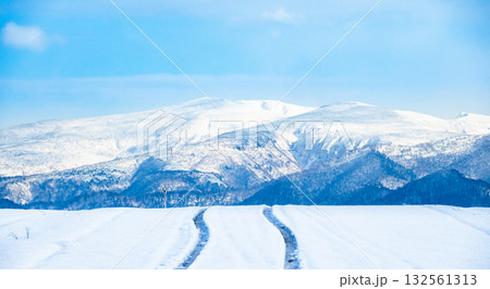 雪の積もった冬の北海道美瑛町の道路に残ったタイヤ跡のある風景 132561313