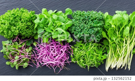 Artistic arrangement of kale and vibrant microgreens on a dark slate background showcasing modern food presentation ideas 132562152