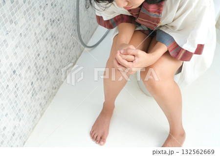 A woman sits on the toilet bowl in the bathroom, and she takes off her panties in the bathroom. She had a stomach ache and was dissatisfied with constipation, diarrhea, food poisoning, health 132562669