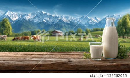 wooden table holds a bottle and glass of milk, with a blurred backdrop of snow-capped mountains, green pastures, and grazing cows wooden table holds a bottle and glass of milk, with a blurred backdrop of snow-capped mountains, green pastures, and grazing cows 132562956