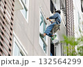 Exterior repair worker rappel down using ropes to repair leaking cement walls residential buildings. 132564299
