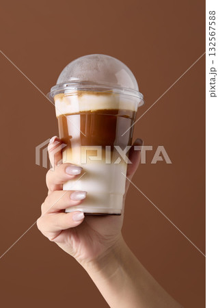 Hand holding iced latte showing barista craft and beverage layering art 132567588
