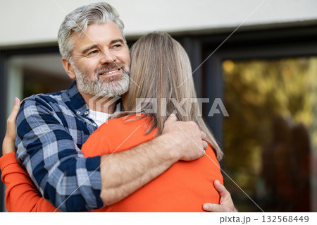 Long-haired woman in orange shirt hugging her husband 132568449