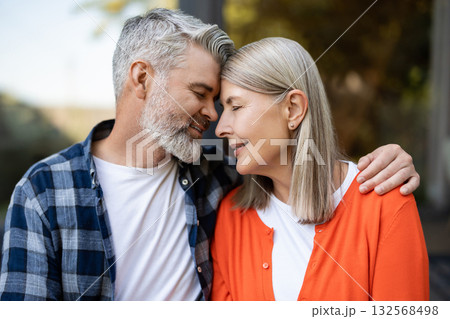 Gray-haired bearded man hugging woman tenderly and both feeling relaxed Gray-haired bearded man hugging woman tenderly and both feeling relaxed 132568498