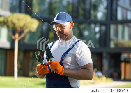 Male landscaper posing outdoors with gardening equipment in hands Male landscaper posing outdoors with gardening equipment in hands 132568540