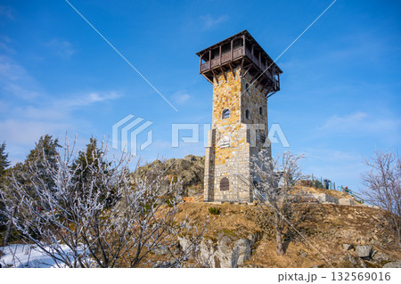 Wysoki Kamien lookout tower stands tall against a clear sky. Surrounded by snow and trees, it offers breathtaking views of the Jizera Mountains. Visitors can enjoy the scenic landscape and fresh air. Wysoki Kamien lookout tower stands tall against a clear sky. Surrounded by snow and trees, it offers breathtaking views of the Jizera Mountains. Visitors can enjoy the scenic landscape and fresh air. 132569016