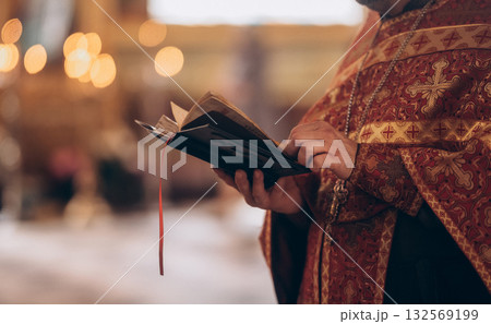 Priest holding Bible during Orthodox church ceremony, close-up Priest holding Bible during Orthodox church ceremony, close-up 132569199
