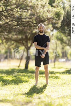 Man standing barefoot contemplating nature in park 132569470