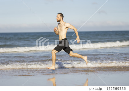 Man running barefoot on a summer ocean beach Man running barefoot on a summer ocean beach 132569586