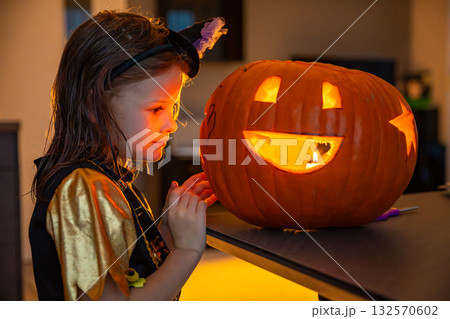 Little girl carving a Halloween pumpkin at home in the evening. Concept of childhood creativity, family tradition, and festive autumn mood. Little girl carving a Halloween pumpkin at home in the evening. Concept of childhood creativity, family tradition, and festive autumn mood. 132570602