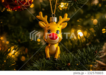 Closeup of the Christmas symbol, cartoon yellow with red nose reindeer Ornament on an illuminated Christmas tree. Closeup of the Christmas symbol, cartoon yellow with red nose reindeer Ornament on an illuminated Christmas tree. 132570803