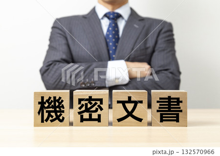 「機密文書」と書かれたブロックと腕組みをするビジネスマン 132570966