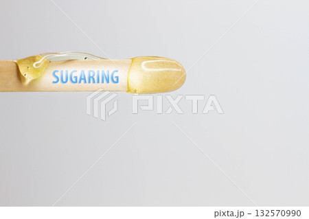 Sugaring inscription on a wooden spatula with hair removal wax. 132570990