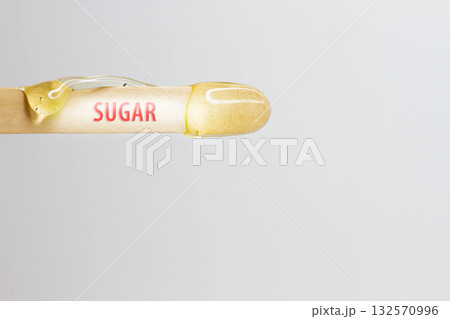 The inscription sugar on a wooden spatula with wax for hair removal. 132570996