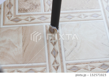 Ripped linoleum. Chair leg and torn linoleum. Hole in linoleum. 132571023