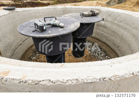 Two underground storage tanks are visible at a construction site in a rural area, with tools resting on top, ready for installation and maintenance 132571170