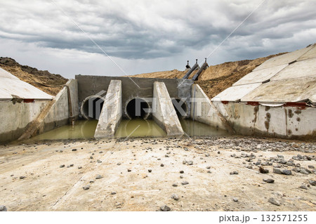 Construction workers develop a stormwater drainage system at a rural site. Heavy machinery is used while cloudy skies appear overhead, indicating possible rain Construction workers develop a stormwater drainage system at a rural site. Heavy machinery is used while cloudy skies appear overhead, indicating possible rain 132571255