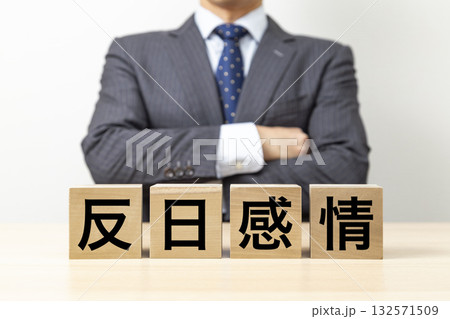 「反日感情」と書かれたブロックと腕組みをするビジネスマン 132571509