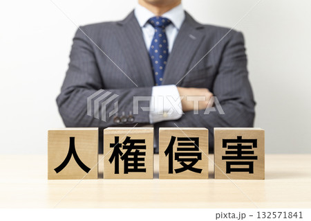 「人権侵害」と書かれたブロックと腕組みをするビジネスマン 「人権侵害」と書かれたブロックと腕組みをするビジネスマン 132571841