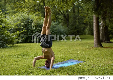 A man mastering the handstand yoga pose in beautiful nature, enjoying the serene environment 132571924