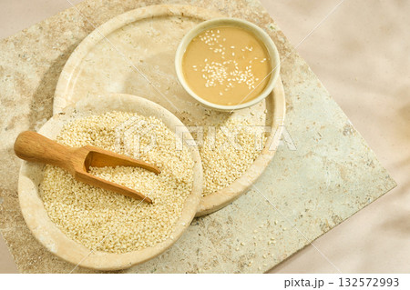 Sesame Tahini Bowl. A bowl of creamy tahini with sesame seeds on a rustic travertine surface. 132572993