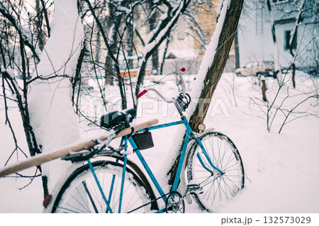 Blue Bicycle Leaning Against Snowy Tree in Quiet Winter Yard Exterior Scene Blue Bicycle Leaning Against Snowy Tree in Quiet Winter Yard Exterior Scene 132573029