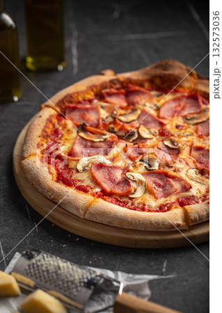 Pizza with ham and mushrooms on black stone table 132573036