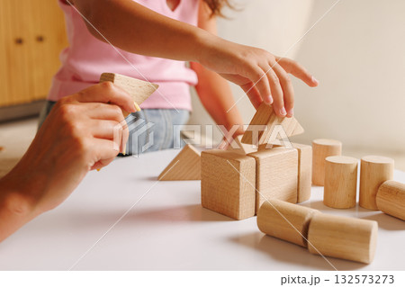 Parent helps preschooler build shapes with wooden blocks, showing play-based learning, fine motor practice, and STEM readiness at home Parent helps preschooler build shapes with wooden blocks, showing play-based learning, fine motor practice, and STEM readiness at home 132573273