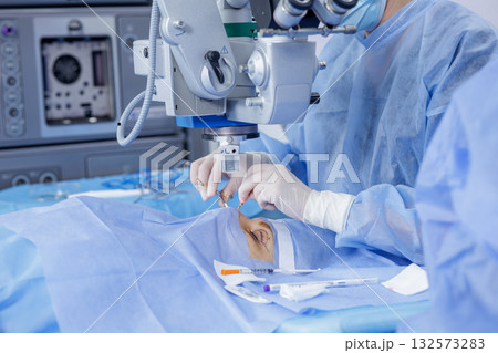 Operating microscope over a marked eyelid as a gloved surgeon performs blepharoplasty in a sterile clinic environment 132573283