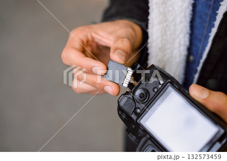 Hand of photographer holding SD memory Card. Male photographer changing SD card of a photo camera outdoors. Young photographer has run out of storage on his memory stick, changes card on his dslr Hand of photographer holding SD memory Card. Male photographer changing SD card of a photo camera outdoors. Young photographer has run out of storage on his memory stick, changes card on his dslr 132573459