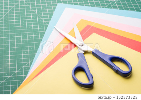 Scissors on a pile of different colorful papers 132573525