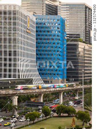 a prominent high-rise building, the BTS Skytrain on an elevated track, and roads with vehicular traffic below, all characteristic of a bustling city center like Bangkok. 132574400