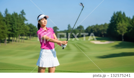 ピンクのゴルフウェアでスイングする女性ゴルファー 132575241