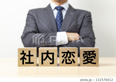 「社内恋愛」と書かれたブロックと腕組みをするビジネスマン 「社内恋愛」と書かれたブロックと腕組みをするビジネスマン 132576012