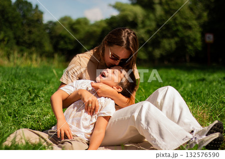 Portrait of young Caucasian single mother hugging her cute small son outside in park sending time on summer day together. Motherhood concept. 132576590