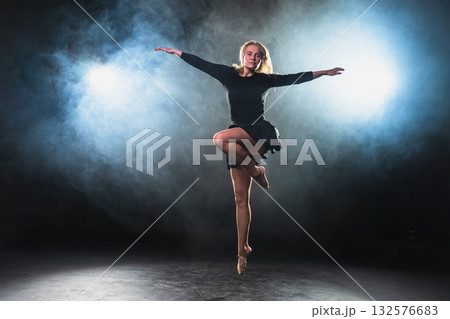 Contemporary woman dancer posing on black background with smoke. Adult female artist performer dancing with expression. Modern ballerina dancing in darkness. Passion dance in dark. Flexibility balance 132576683