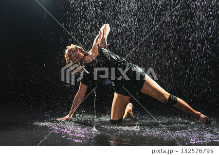 Contemporary woman dancer posing in rain water on black background. Female artist performer dancing with expression. Modern ballerina dancing in darkness. Passion dance in dark. Flexibility balance Contemporary woman dancer posing in rain water on black background. Female artist performer dancing with expression. Modern ballerina dancing in darkness. Passion dance in dark. Flexibility balance 132576795