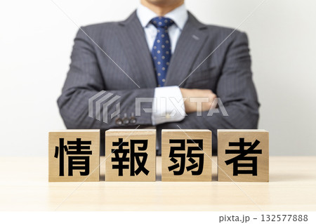 「情報弱者」と書かれたブロックと腕組みをするビジネスマン 「情報弱者」と書かれたブロックと腕組みをするビジネスマン 132577888