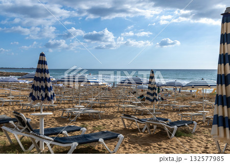Golden sand beach with empty sun loungers and umbrellas 132577985