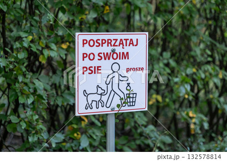 A public sign encouraging dog owners to clean up after their pets, promoting urban cleanliness and responsible pet ownership in a park setting A public sign encouraging dog owners to clean up after their pets, promoting urban cleanliness and responsible pet ownership in a park setting 132578814