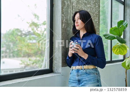Serious tired, stressed businesswoman standing near window Serious tired, stressed businesswoman standing near window 132578859