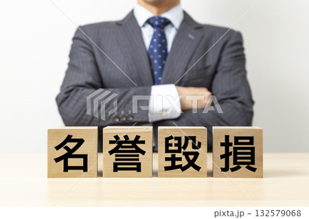 「名誉毀損」と書かれたブロックと腕組みをするビジネスマン 「名誉毀損」と書かれたブロックと腕組みをするビジネスマン 132579068